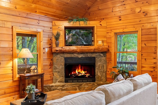 living room featuring wood ceiling, lofted ceiling, a stone fireplace, and wood walls