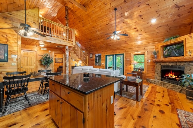 kitchen featuring a stone fireplace, wood walls, light hardwood / wood-style flooring, wooden ceiling, and ceiling fan