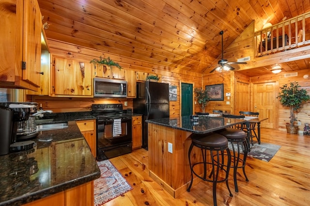 kitchen featuring wooden ceiling, wooden walls, a kitchen island, light hardwood / wood-style floors, and black appliances