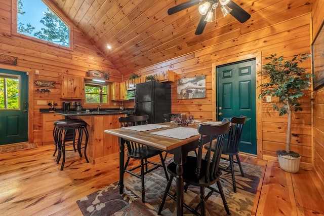 dining space featuring high vaulted ceiling, wood ceiling, light hardwood / wood-style floors, and wood walls