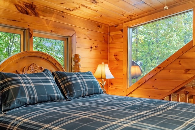 bedroom featuring wooden walls, multiple windows, and wooden ceiling