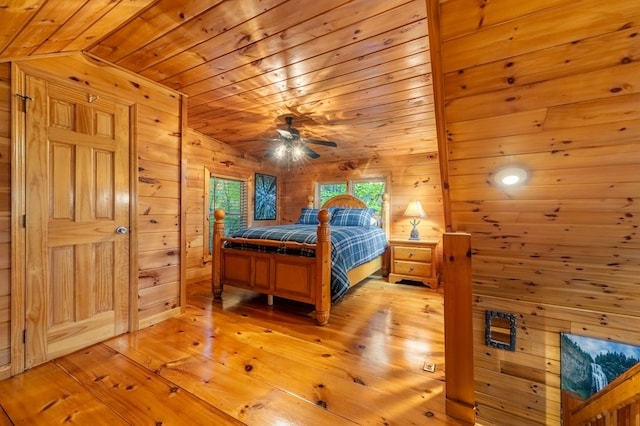 bedroom with wood ceiling, vaulted ceiling, light wood-type flooring, and wood walls