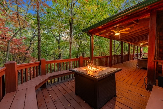 wooden terrace featuring ceiling fan and a fire pit