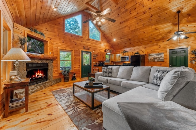 living room with wooden ceiling, a stone fireplace, light wood-type flooring, and wood walls