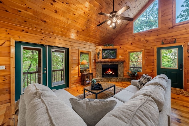 living room with light hardwood / wood-style flooring, high vaulted ceiling, a fireplace, wooden ceiling, and wood walls