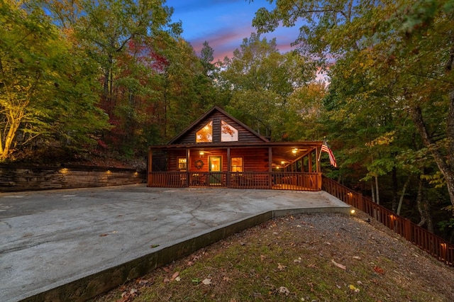 back house at dusk featuring a porch