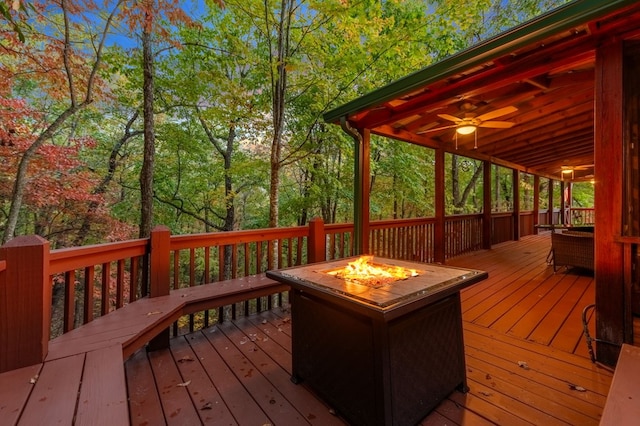 wooden terrace featuring ceiling fan and a fire pit