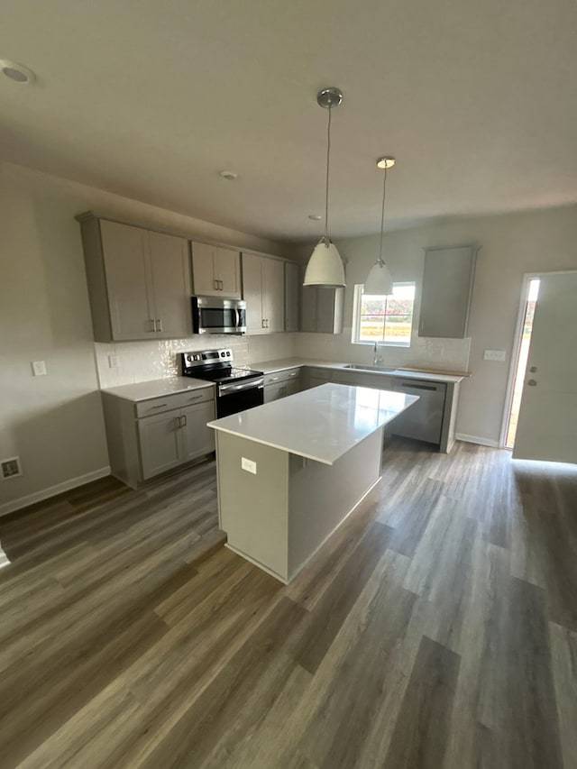 kitchen featuring stainless steel appliances, sink, gray cabinets, a kitchen island, and hanging light fixtures