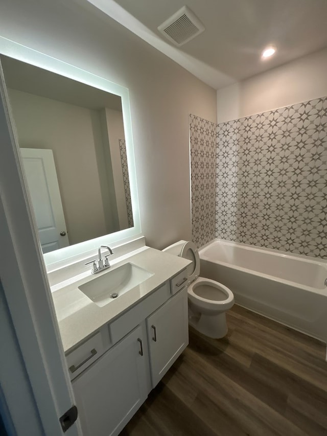 full bathroom featuring hardwood / wood-style floors, vanity, tub / shower combination, and toilet