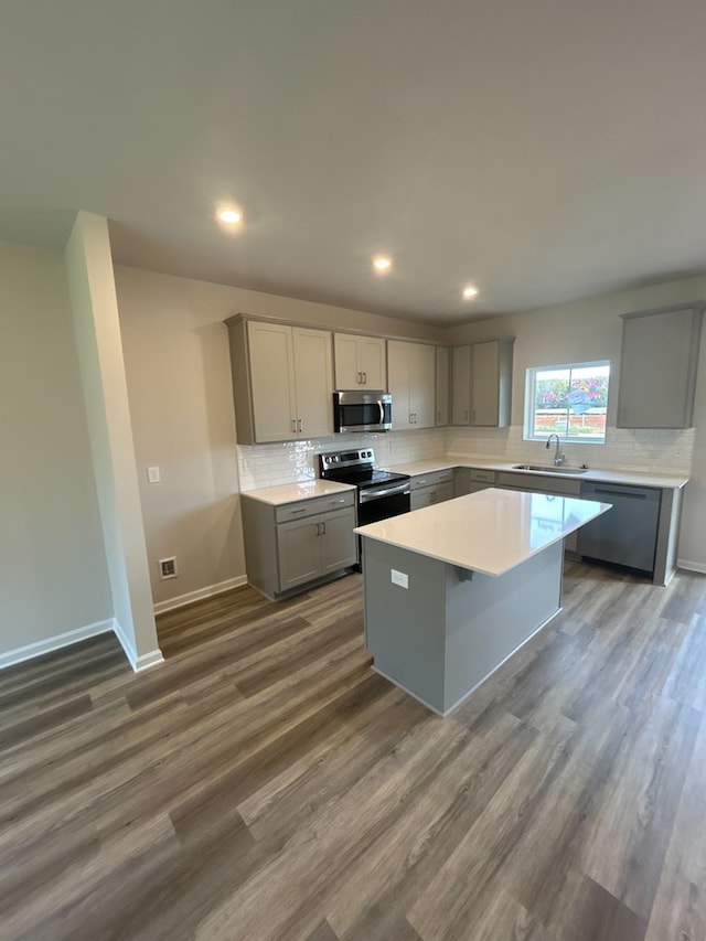 kitchen featuring a center island, dark wood-type flooring, sink, gray cabinets, and stainless steel appliances