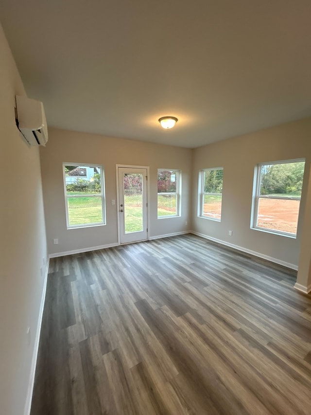 empty room featuring plenty of natural light, dark hardwood / wood-style floors, and an AC wall unit