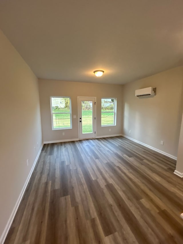 spare room featuring dark hardwood / wood-style flooring and a wall unit AC