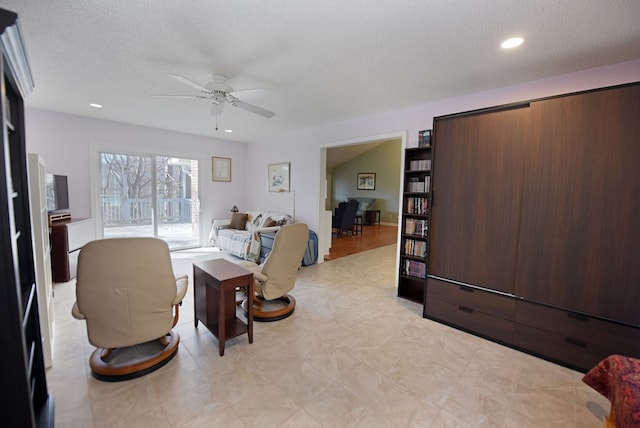 living room with ceiling fan and a textured ceiling