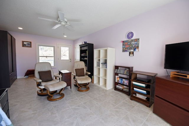 living area with ceiling fan, a textured ceiling, and light tile patterned floors