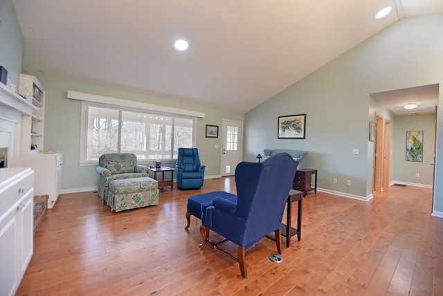 living room featuring high vaulted ceiling and light hardwood / wood-style floors