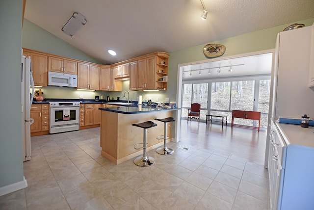 kitchen featuring vaulted ceiling, sink, a kitchen bar, light tile patterned floors, and white appliances