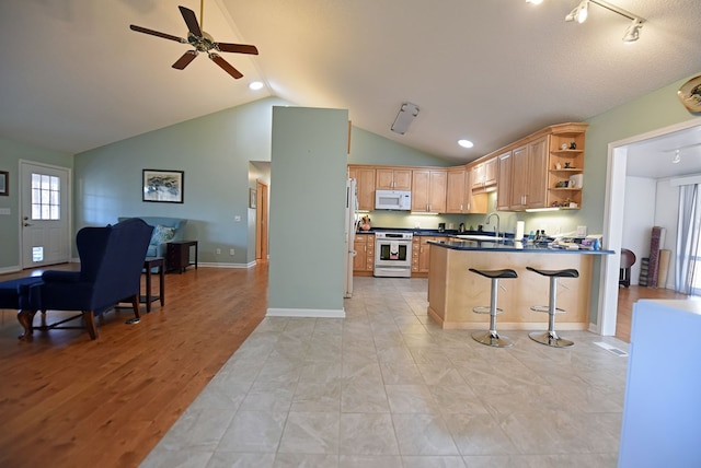 kitchen featuring lofted ceiling, sink, a breakfast bar area, kitchen peninsula, and white appliances