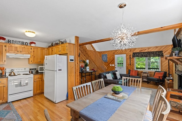 dining area featuring an inviting chandelier, light hardwood / wood-style flooring, and wood walls