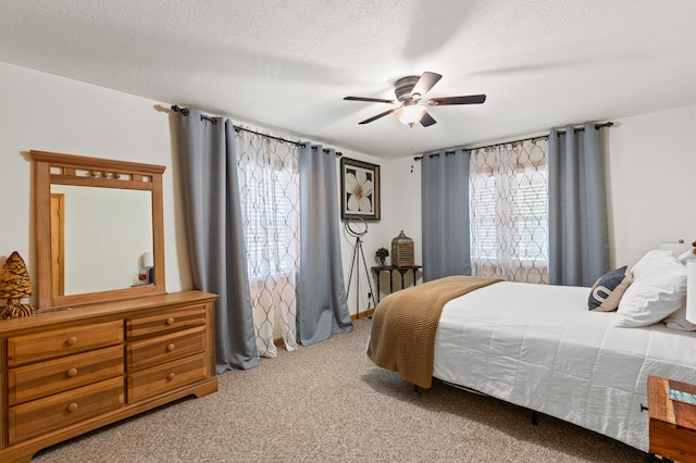 bedroom with ceiling fan, carpet floors, and a textured ceiling