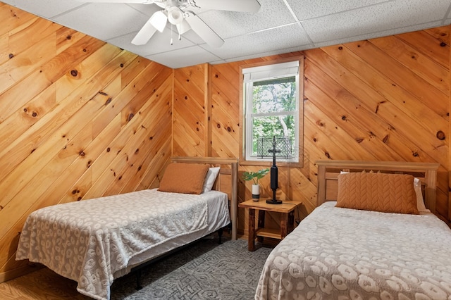 bedroom with ceiling fan and wooden walls