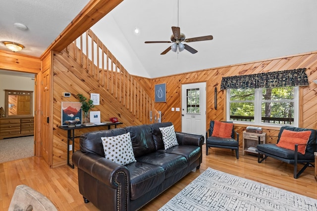 living room featuring hardwood / wood-style flooring, ceiling fan, lofted ceiling, and wooden walls