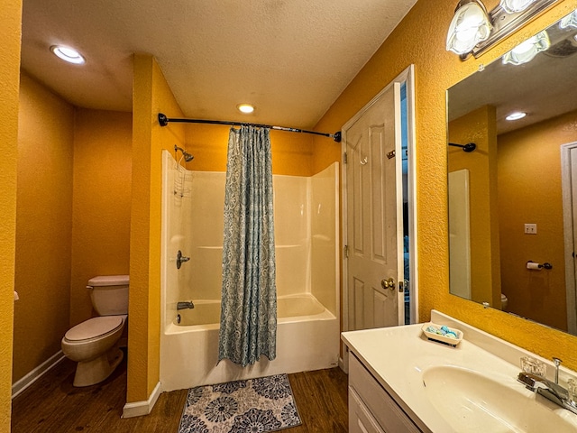 full bathroom featuring hardwood / wood-style flooring, a textured ceiling, toilet, shower / bath combo with shower curtain, and vanity