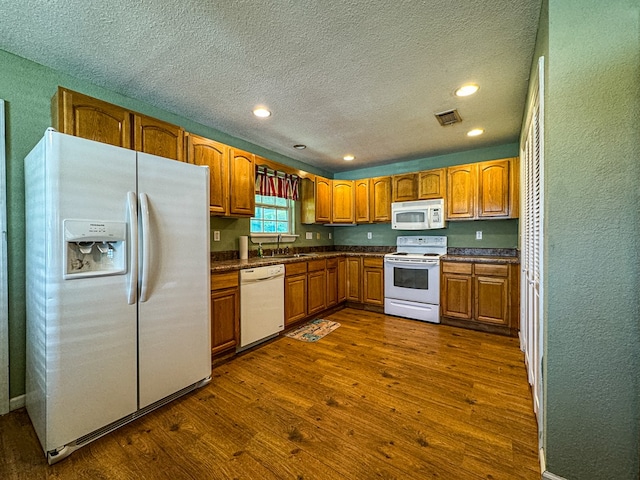 kitchen featuring sink, white appliances, dark hardwood / wood-style flooring, and a textured ceiling