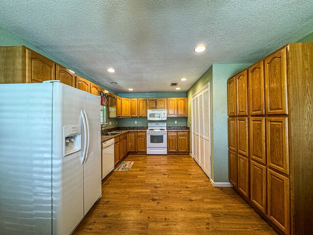 kitchen featuring white appliances, hardwood / wood-style floors, sink, and a textured ceiling