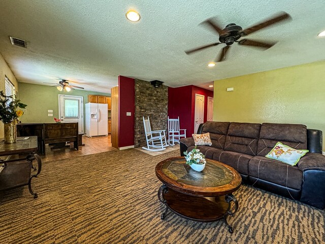 carpeted living room with a textured ceiling and ceiling fan