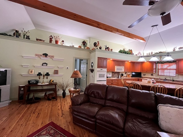 living room featuring light wood-type flooring, vaulted ceiling with beams, and ceiling fan