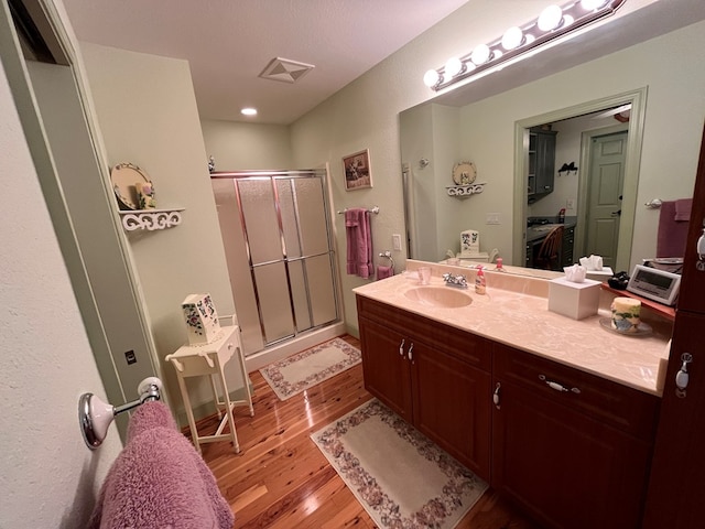 bathroom with walk in shower, vanity, a textured ceiling, and hardwood / wood-style flooring