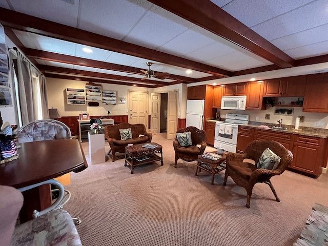 carpeted living room featuring ceiling fan, sink, and beamed ceiling