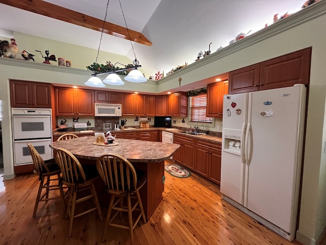 kitchen featuring a center island, sink, high vaulted ceiling, light hardwood / wood-style floors, and white appliances