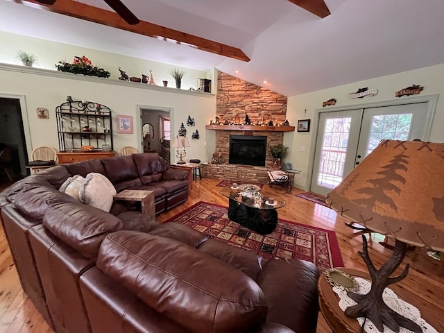 living room with ceiling fan, french doors, vaulted ceiling with beams, light hardwood / wood-style flooring, and a fireplace