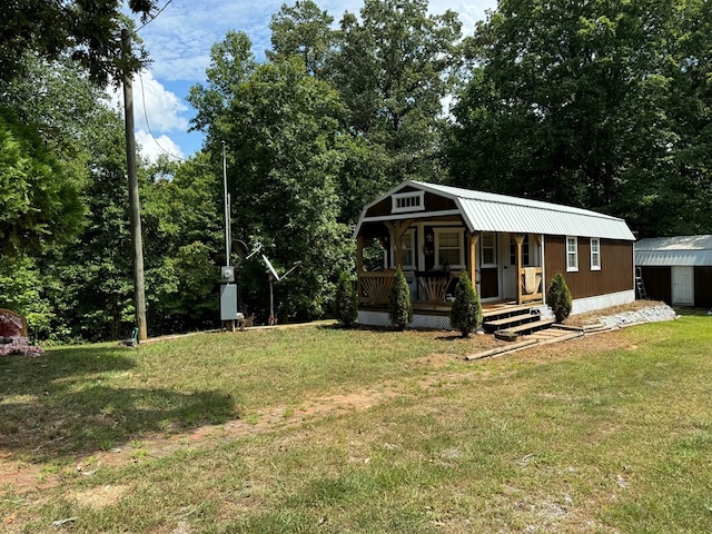 view of front of house featuring covered porch, an outdoor structure, and a front yard