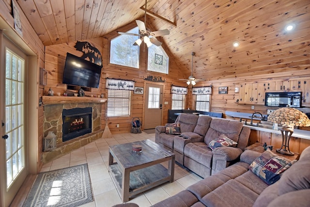 living room featuring light tile patterned floors, a stone fireplace, wooden walls, wooden ceiling, and high vaulted ceiling