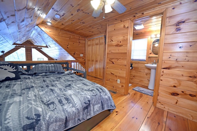 bedroom featuring wood ceiling, wooden walls, ceiling fan, light hardwood / wood-style flooring, and sink