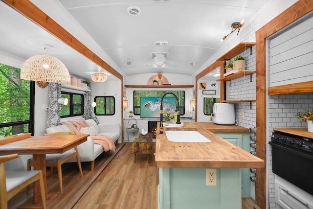 kitchen featuring backsplash, ceiling fan with notable chandelier, butcher block counters, hanging light fixtures, and green cabinets