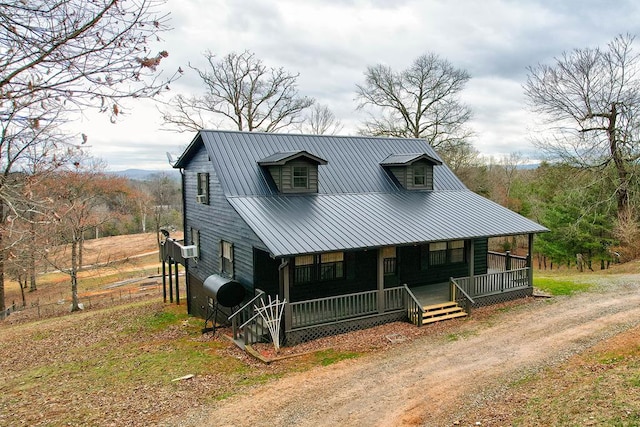 view of front facade with covered porch, dirt driveway, metal roof, and heating fuel