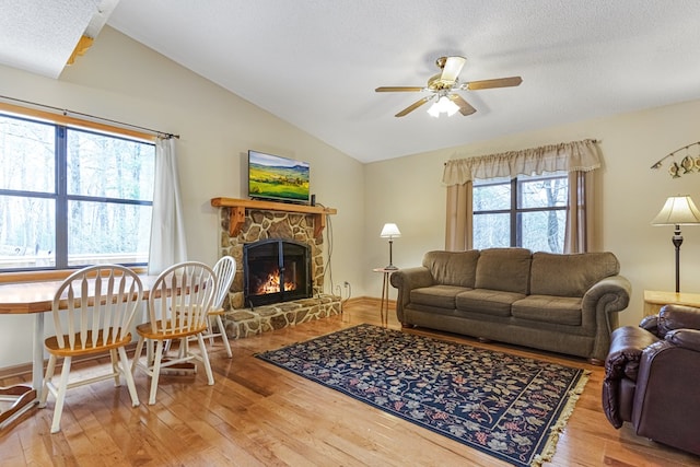 living room with hardwood / wood-style floors, vaulted ceiling, a fireplace, and ceiling fan