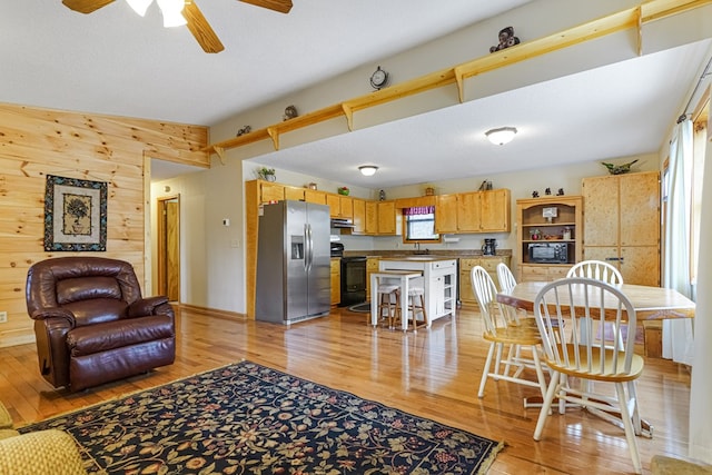 living room featuring a ceiling fan, light wood-type flooring, wood walls, and a textured ceiling