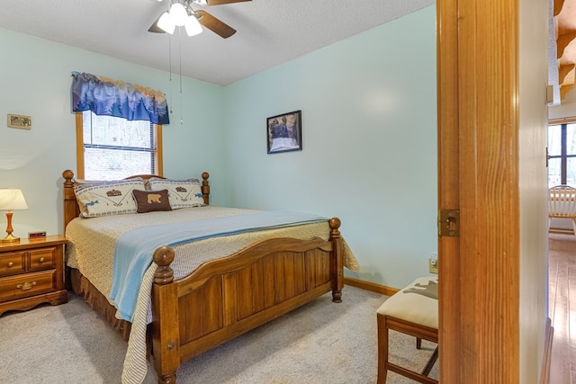 carpeted bedroom featuring baseboards, a textured ceiling, and a ceiling fan