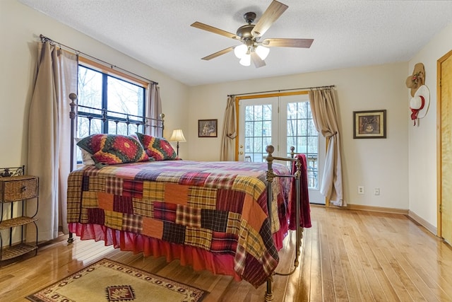 bedroom featuring light wood-style flooring, a textured ceiling, baseboards, and ceiling fan