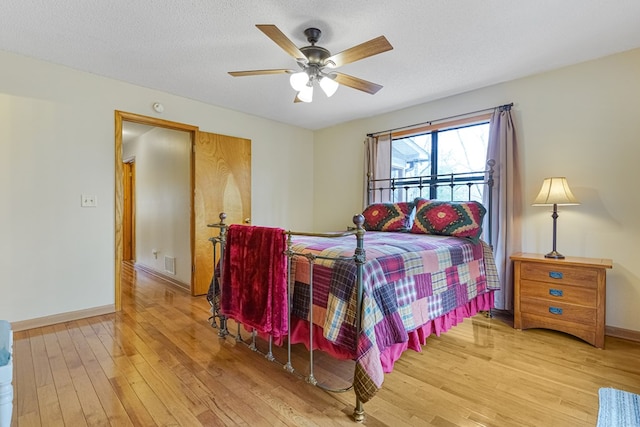 bedroom with baseboards, a textured ceiling, light wood-style flooring, and a ceiling fan