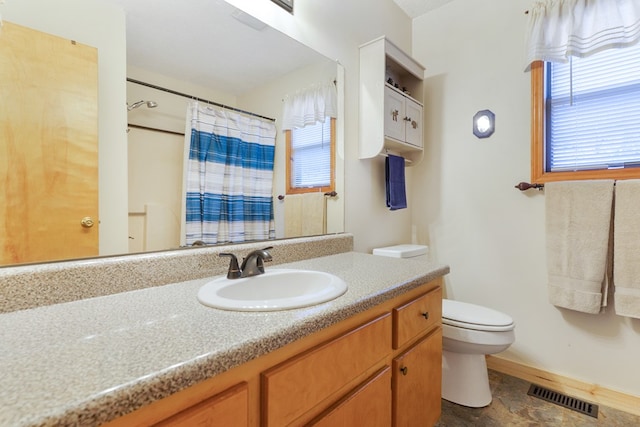 bathroom featuring visible vents, a healthy amount of sunlight, toilet, and vanity