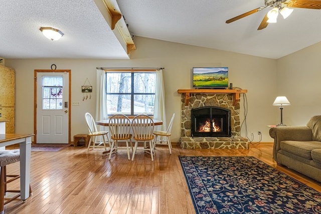 living area featuring hardwood / wood-style floors, lofted ceiling, a fireplace, and a wealth of natural light