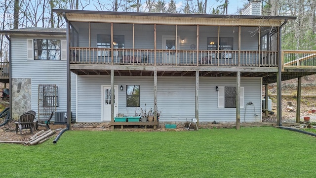 rear view of house with a yard, cooling unit, a sunroom, and a chimney