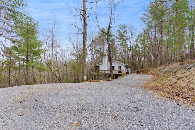 view of side of home with a wooden deck, driveway, and a chimney