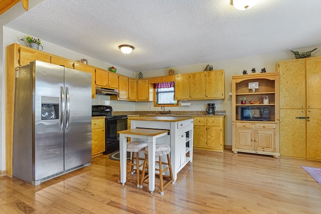 kitchen with a sink, under cabinet range hood, light wood-style flooring, black appliances, and open shelves