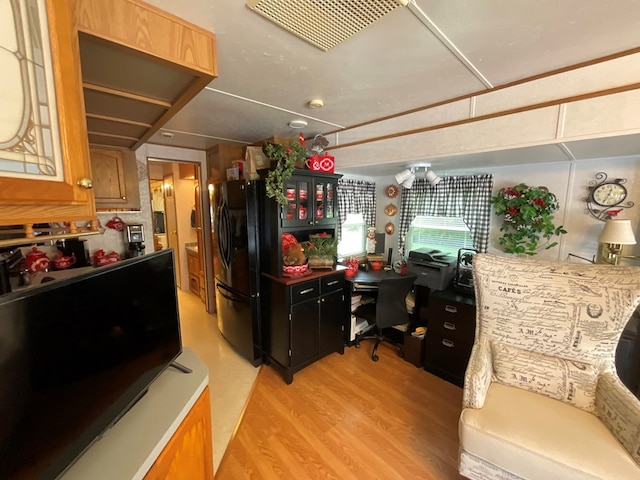 kitchen with light hardwood / wood-style floors and black fridge